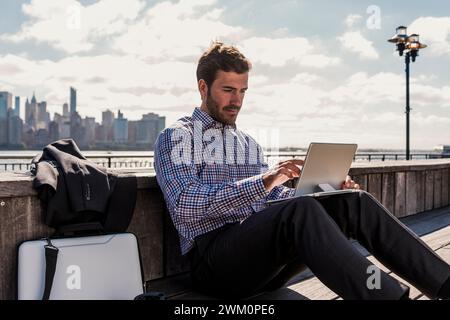 Businessman using tablet PC sitting on bench in city Stock Photo