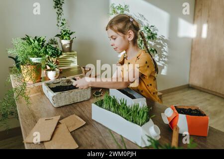 Creative girl upcycling milk carton into pot at home Stock Photo