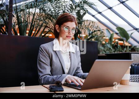 Businesswoman working on laptop in office cafeteria Stock Photo