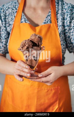Woman wearing apron and holding chocolate ice cream in hand Stock Photo
