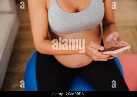 Pregnant woman using smart phone at home Stock Photo