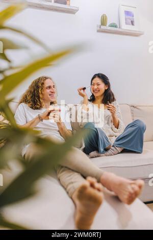 Happy couple sitting on sofa and having fun at home Stock Photo