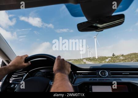 Spain, Madrid, Hands of man driving past wind farm Stock Photo