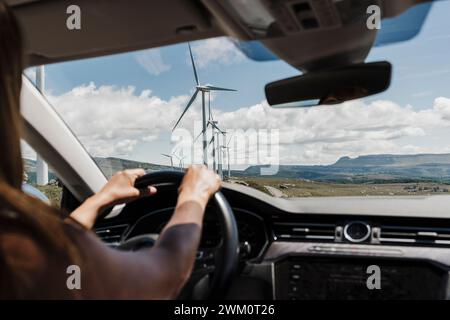 Spain, Madrid, Hands of woman driving past wind farm Stock Photo