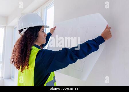 Smiling architect examining blueprint at site Stock Photo