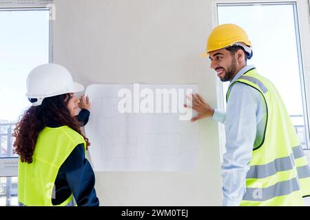 Architects discussing over blueprint on wall at site Stock Photo