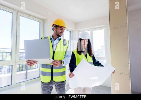 Architects discussing over blueprint at site Stock Photo