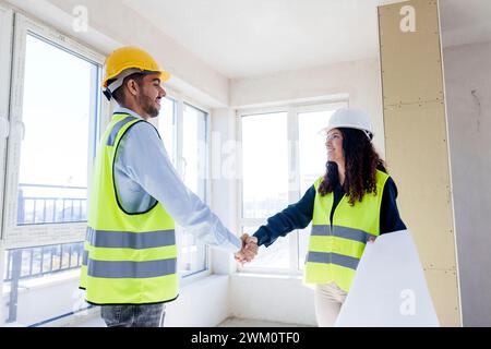 Smiling architects shaking hands at site Stock Photo