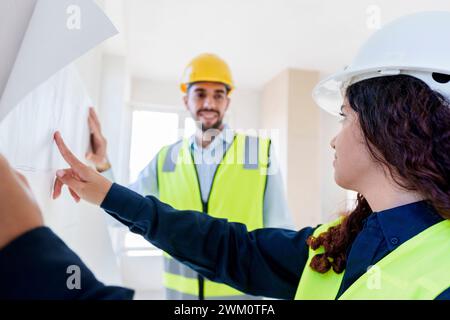 Architects discussing over blueprint at construction site Stock Photo