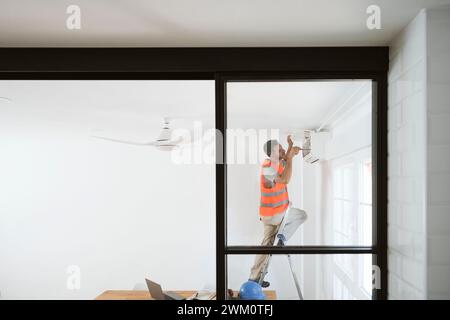 Mature technician fixing air conditioner in house under renovation Stock Photo