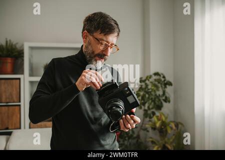 Man putting photograph in old instant camera at home Stock Photo