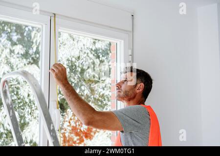 Mature technician measuring window at home Stock Photo