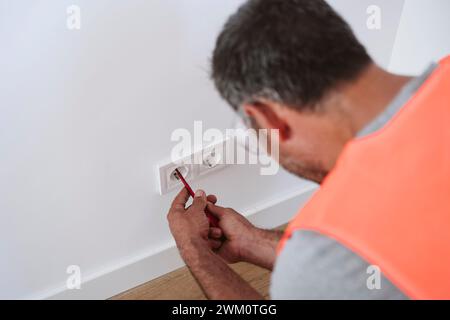 Mature technician repairing electrical outlet at home Stock Photo