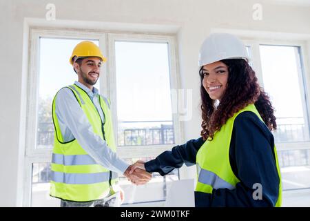 Happy engineer shaking hand with colleague at site Stock Photo