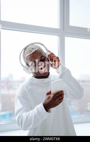 Smiling man wearing wireless headphones and using smart phone Stock Photo