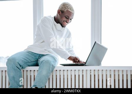 Happy freelancer using laptop near window at home Stock Photo