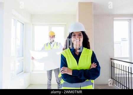 Confident young architect standing with arms crossed at site Stock Photo