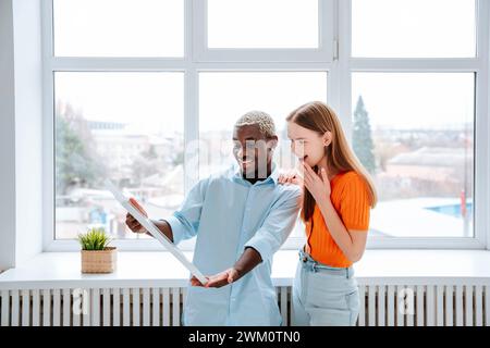 Happy man showing solar panel to surprised woman at home Stock Photo