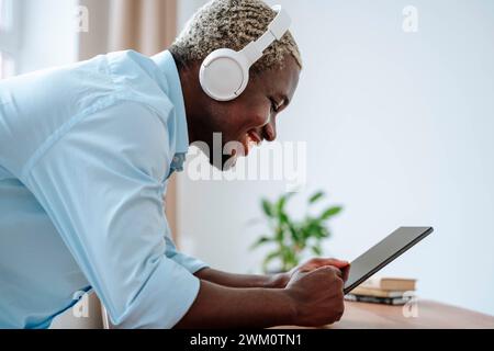 Happy man wearing wireless headphones and using tablet PC Stock Photo