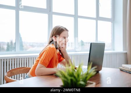 Happy young freelancer using laptop at desk Stock Photo