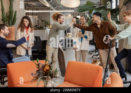 Happy diverse colleagues giving high-five to each other in meeting at office Stock Photo