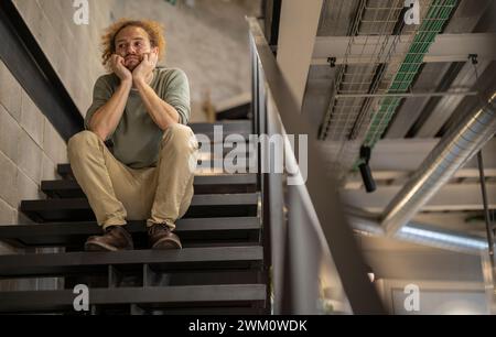 Upset businessman sitting on staircase at office Stock Photo