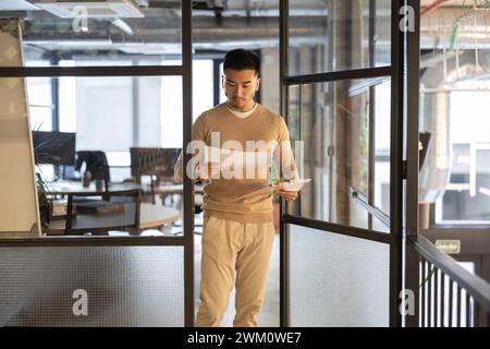 Young businessman with documents walking through door at office Stock Photo