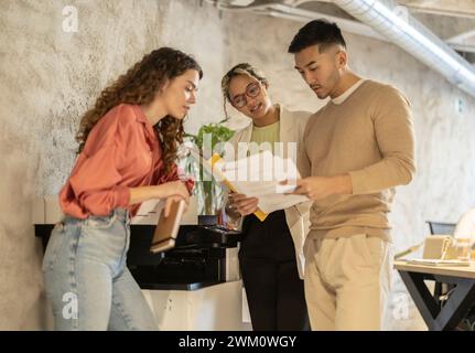 Young business colleagues discussing over documents standing by wall at office Stock Photo