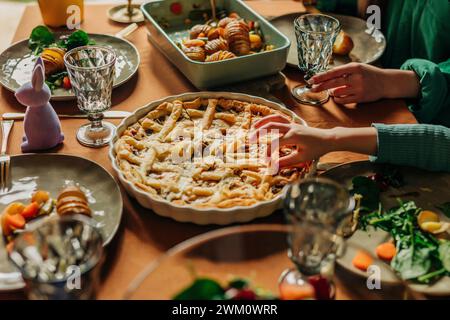 Family having freshly baked pie kept on dining table at Easter dinner Stock Photo