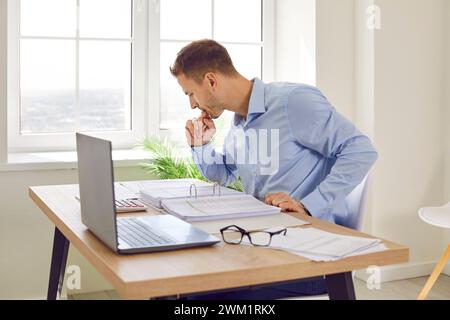 Prtrait of a young businessman looking through paper documents and working at office. Stock Photo