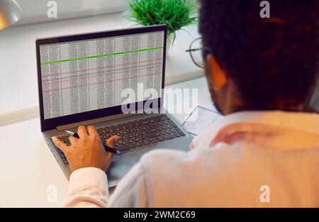 Businessman or accountant sitting at office desk and working with spreadsheets on laptop Stock Photo