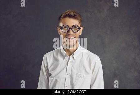 Studio portrait of cheerful young man wearing funny glasses with magnifying lenses. Stock Photo