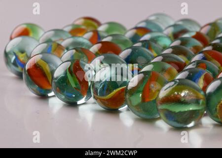 Close-up of a group of colorful glass marbles isolated against a white background with natural shadows Stock Photo