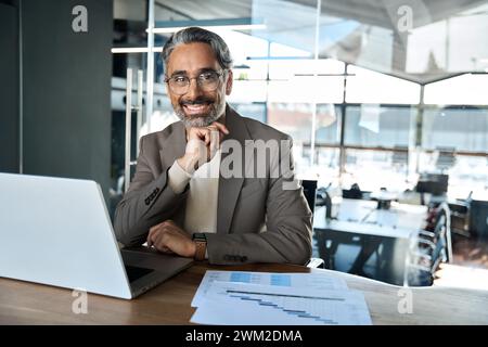 Portrait of happy middle aged business man looking at camera at work desk. Stock Photo