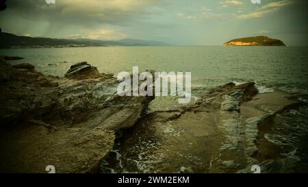 Rocky beach in dusk lights with a thunderstorm coming. Beautiful greek landscape image Greece, Fidonisi island Stock Photo