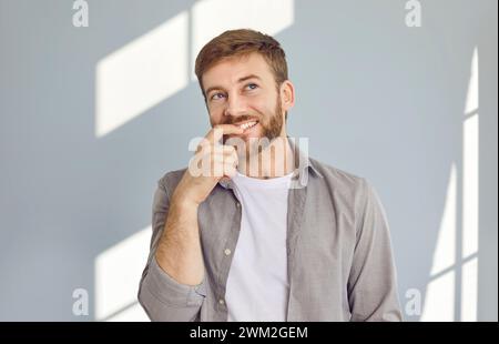 Portrait of happy young man thinking, daydreaming, imagining something, and smiling Stock Photo