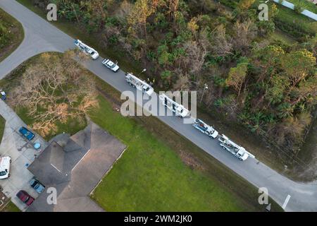Electrician workers repairing damaged power lines using bucket trucks after hurricane in Florida residential area. Stock Photo