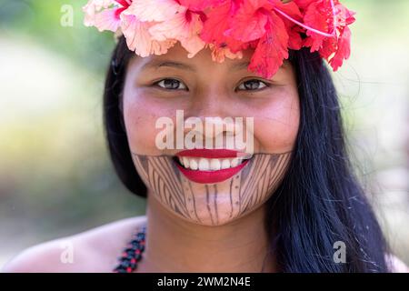 Smiling young woman from Embera tribe from a village in Chagres national park with traditional tattoos on her face and flowers in her hair, Panama Stock Photo