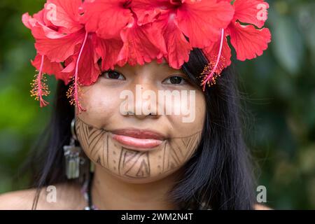 Beautiful woman from Embera tribe from a village in Chagres national park with traditional tattoos on her face and hibiscus flowers in hair, Panama Stock Photo