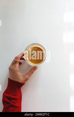 Female hand holding a cup of espresso on the white table, top view Stock Photo
