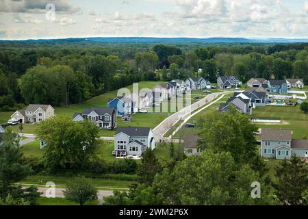 Upscale suburban homes with large backyards and green grassy lawns in summer season. Private residential houses in rural suburban sprawl area in Stock Photo