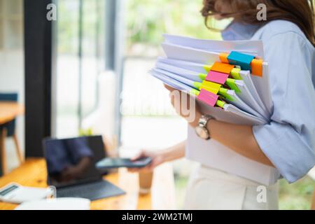 A young secretary receives a pile of documents to find important information for the company manager to use in a meeting. The concept of finding impor Stock Photo