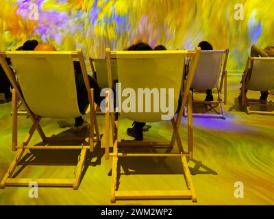 Part view of a show with amazing light projection in various colors and people relaxing in the deck chairs Stock Photo