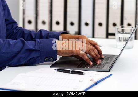 Closeup shot of an unrecognizable man using a laptop while working from office Stock Photo