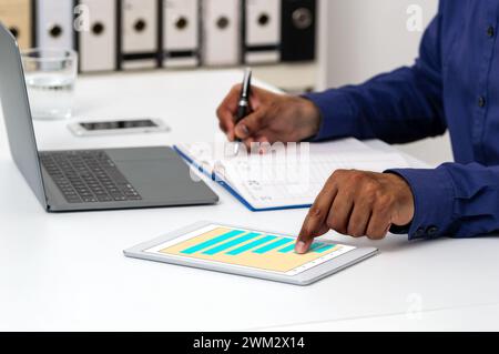 Shot of an unrecognizable businessman using a digital tablet with graphs on it in a modern office Stock Photo