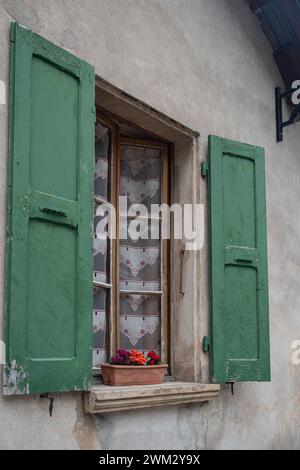 Exterior windowsill with antique curtains and green wooden shutters Stock Photo