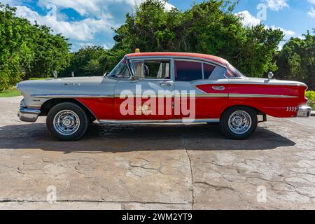 Cuba 14 Feb 2016 - A red and white vintage car in a parking area under a blue sky in Cayo Santa Maria, Cuba. Stock Photo