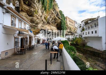 Typical street in Setenil de las Bodegas with restaurants and houses inside the rocks of the mountain and tourists walking around, Cadiz, Spain. Stock Photo