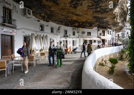 Typical street Caves of the sun in Setenil with restaurants and houses inside the rocks of the mountain and tourists walking around, Cadiz, Spain. Stock Photo