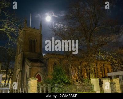 Sheerness, Kent, UK. 23rd Feb, 2024. UK Weather: the almost full Snow Moon above Holy Trinity Church in Sheerness, Kent this evening.  Credit: James Bell/Alamy Live News Stock Photo